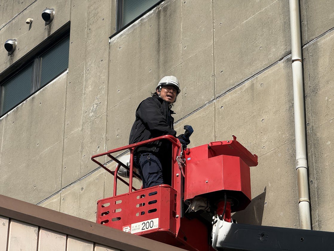 高所作業車で建物の点検・施工をするメンバー