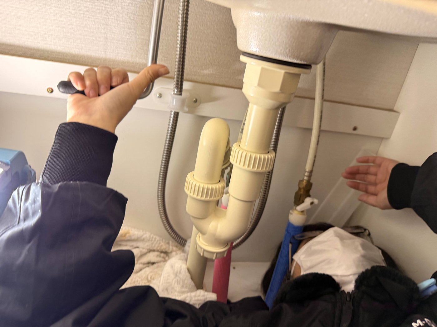 キッチン下の排水管を点検するメンバー